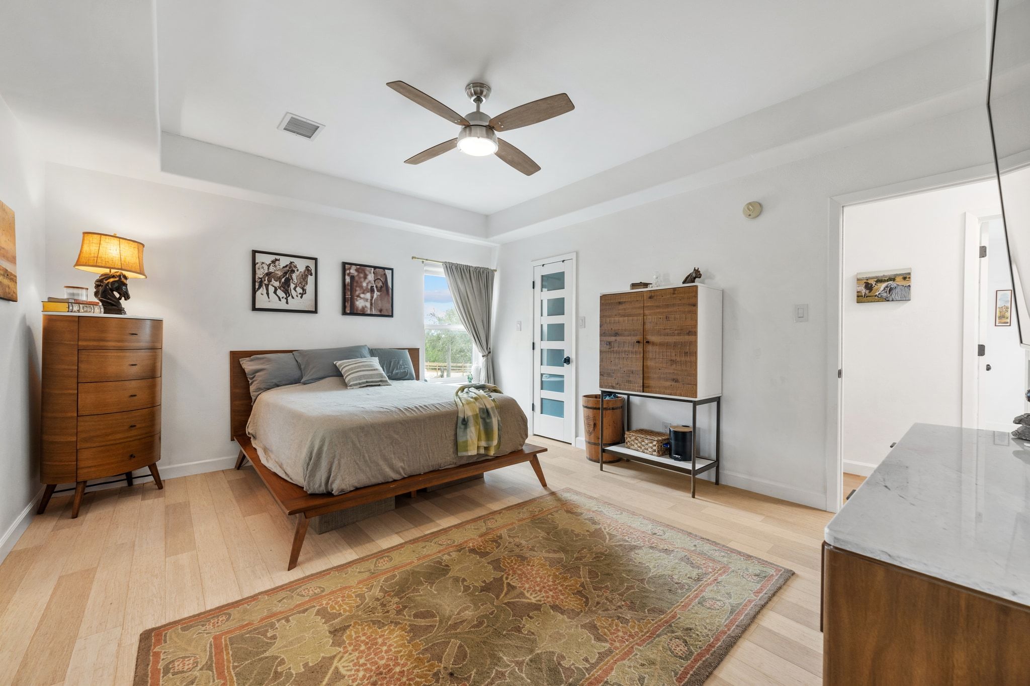 401 Ranchview Drive Johnson City, TX 78636 - Photo 22 of 40 Bedroom with light wood-type flooring, a ceiling fan, and a tray ceiling