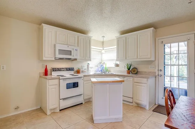 a kitchen with stainless steel appliances granite countertop a stove a sink and white cabinets