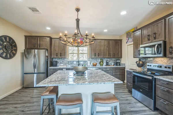 a kitchen with stainless steel appliances granite countertop a kitchen island a stove a table and chairs