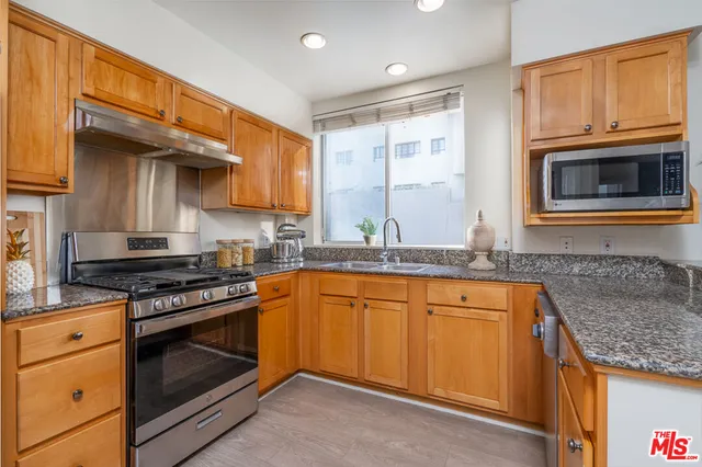 a kitchen with granite countertop stainless steel appliances a stove sink and microwave