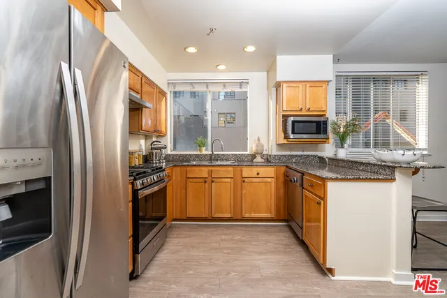 a kitchen with stainless steel appliances granite countertop a refrigerator stove top oven and sink