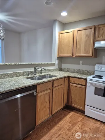 a kitchen with granite countertop cabinets sink and white appliances