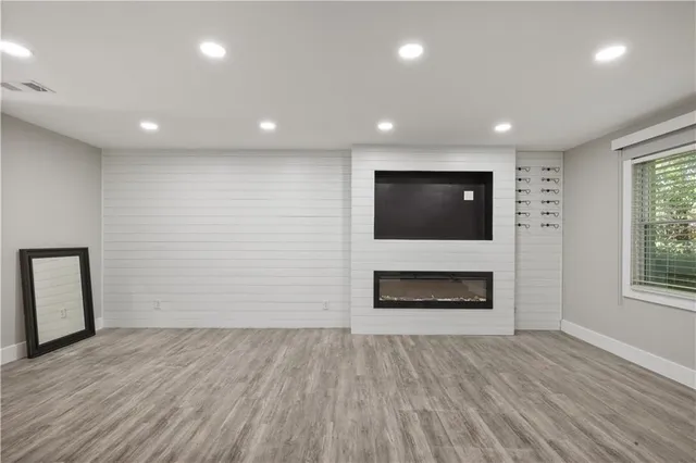 an empty room with wooden floor fireplace and windows