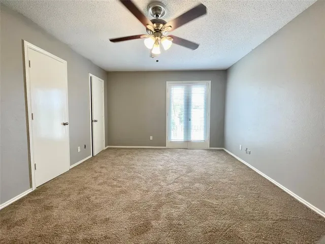 an empty room with a chandelier fan and windows