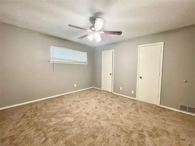 an empty room with a fan & a window