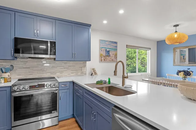 a kitchen with granite countertop a sink stainless steel appliances and cabinets