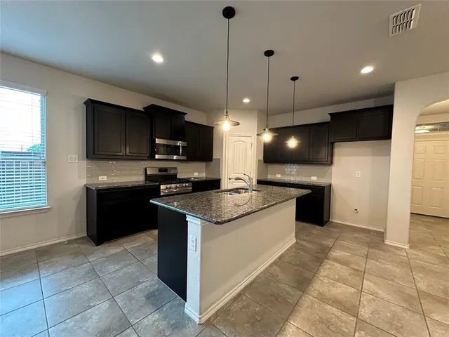 a large kitchen with stainless steel appliances granite countertop a sink and a stove
