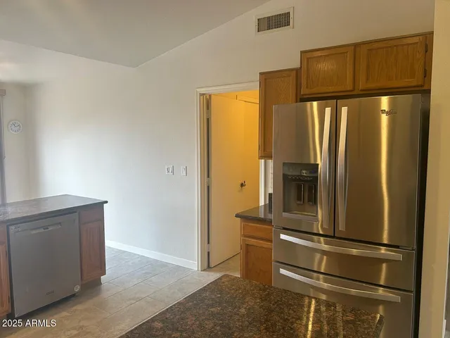 a kitchen with kitchen island granite countertop a sink counter top space a refrigerator and cabinets