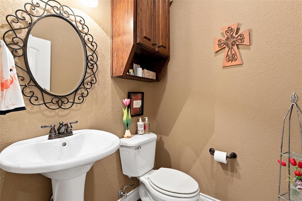 845 County Line Road West West, TX 76691 - Photo 24 of 36 Pedestal sink with a two-handle bronze-finish faucet, oval mirror with an ornate black iron frame, and a wall-mounted wood-finish cabinet