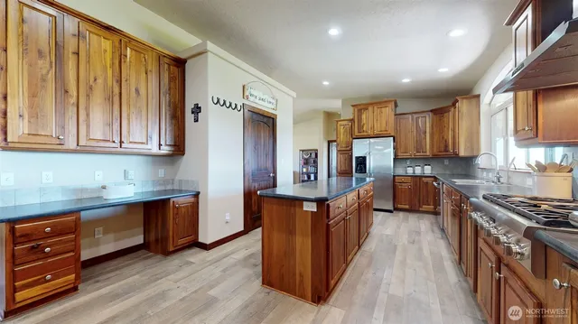a kitchen with stainless steel appliances granite countertop wooden cabinets a refrigerator a sink and a stove