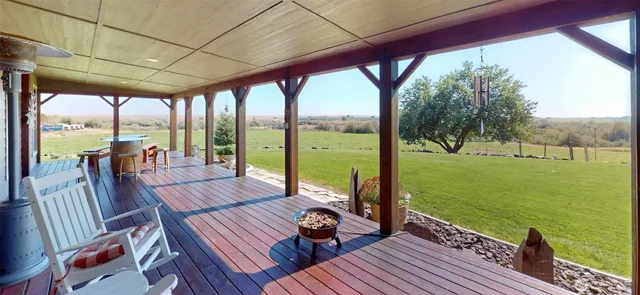 a view of a patio with lawn chairs floor to ceiling window next to a yard