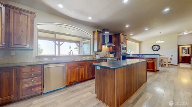 a kitchen with stainless steel appliances granite countertop a sink a stove and a wooden floors