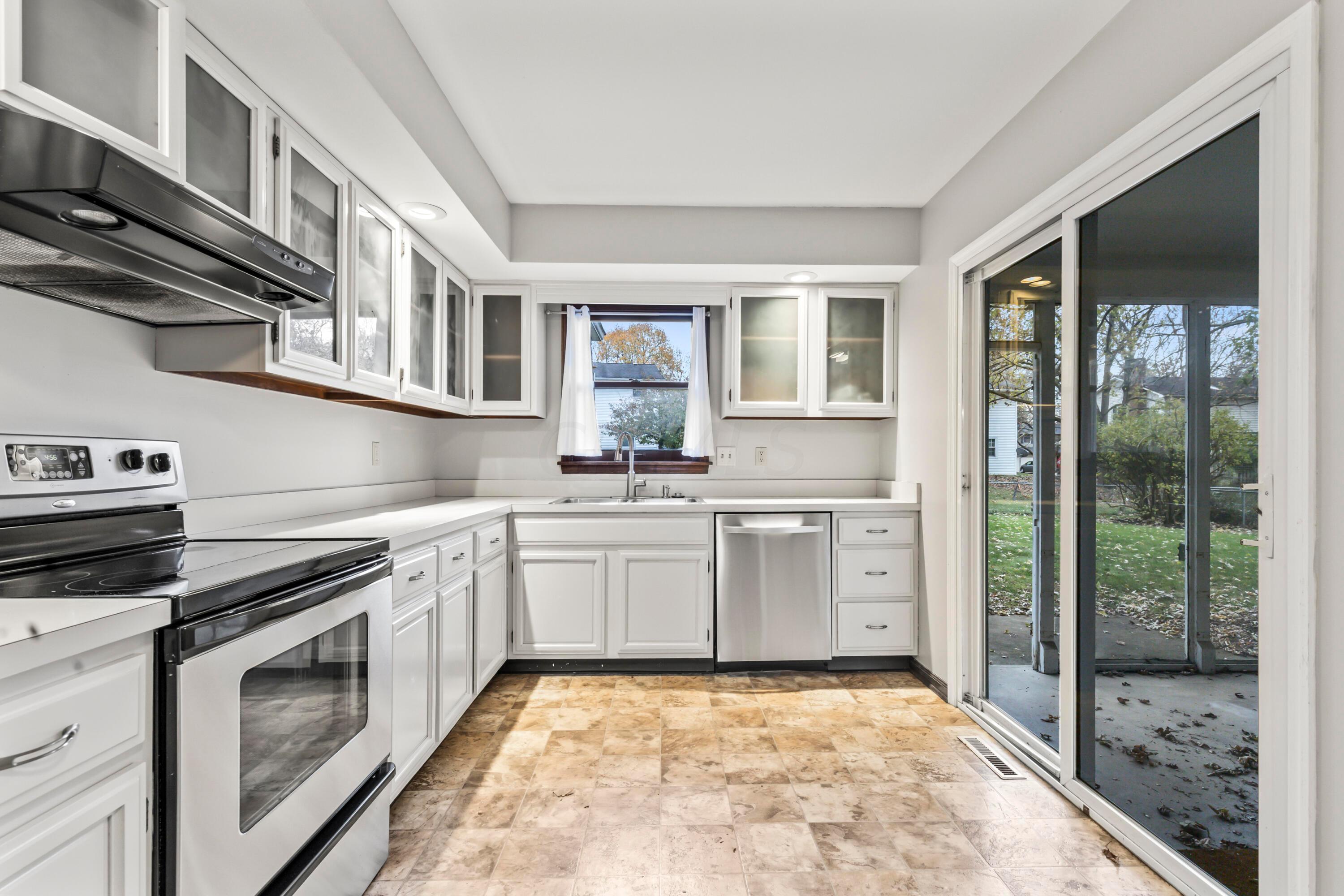 7020 Rieber Street Columbus, OH 43085 - Photo 11 of 40 • New neutral vinyl flooring ~ 2006 • Grey painted walls • Raised panel, white painted cabinets with glass fronts • New Whirlpool® refrigerator ~ 2017 • New Whirlpool® electric range ~ 2017 • Allure® rangehood • New Kenmore® dishwasher ~ 2017 • Double bowl, stainless steel sink with sprayer • New disposal • Can lighting • New sliding doors to screened porch • Planning desk • Buffet/media center • Pantry closet • Sliding doors to Screened Porch