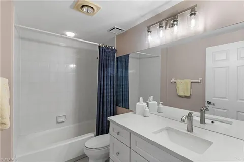 a bathroom with a bathtub shower sink vanity mirror and toilet