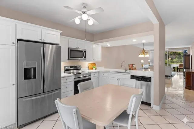 a kitchen with stainless steel appliances a refrigerator a stove a sink a dining table and chairs