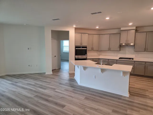 a large kitchen with stainless steel appliances kitchen island granite countertop a stove a sink and a refrigerator