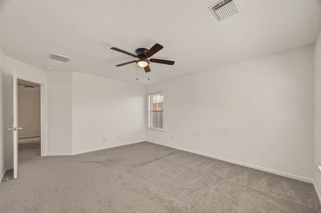 an empty room with a ceiling fan and window