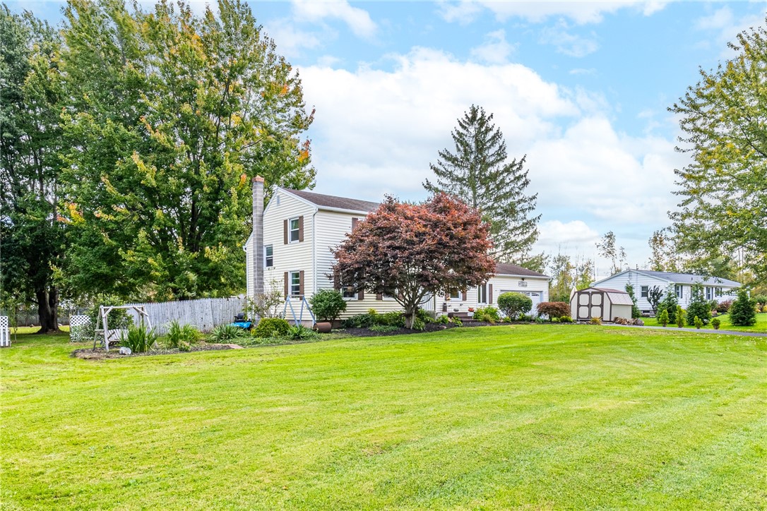 Mature trees frame a classic two-story residence situated on an expansive green lawn.
