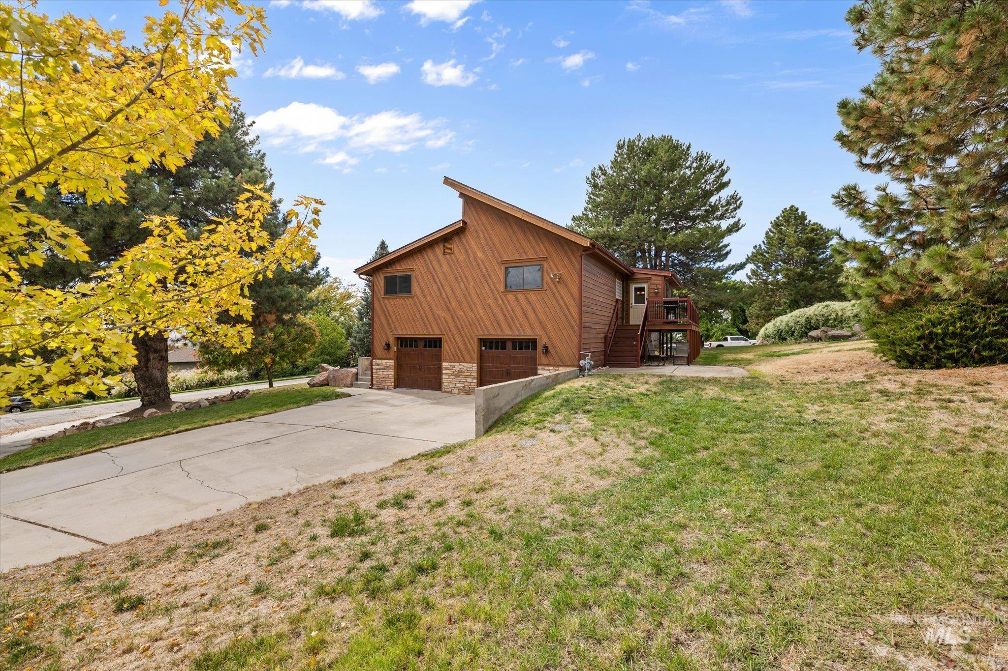 2199 South Ridge Point Way Boise, ID 83712 - Photo 39 of 50 View of home's exterior featuring stairway, a garage, concrete driveway, stone siding, and a lawn