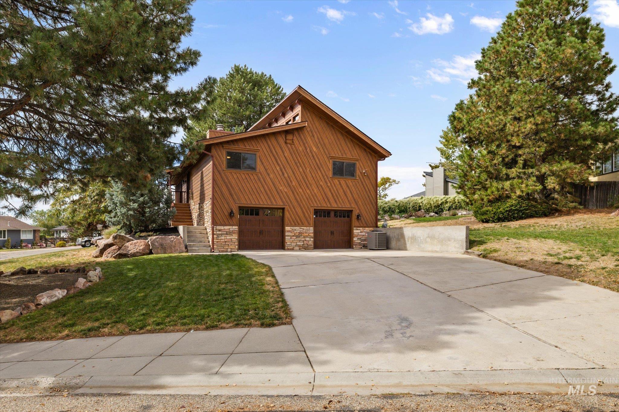2199 South Ridge Point Way Boise, ID 83712 - Photo 40 of 50 View of side of home featuring stone siding, driveway, a lawn, a chimney, and a garage