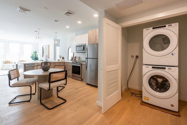 a living room with furniture a washer and dryer with kitchen view