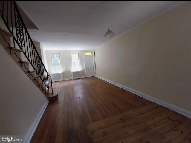 an empty room with wooden floor and staircase