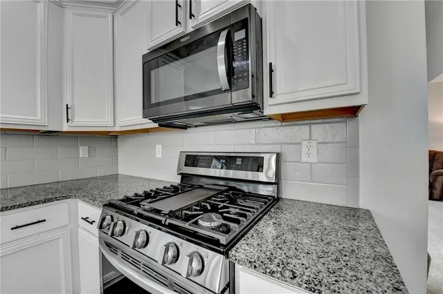 a kitchen with stainless steel appliances granite countertop a stove top oven a refrigerator a sink and dishwasher with wooden floor