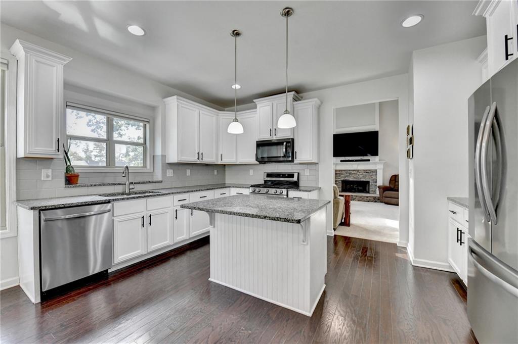 533 Widgeon Way Jefferson, GA 30549 - Photo 37 of 101 a kitchen with stainless steel appliances granite countertop a stove top oven a refrigerator a sink and dishwasher with wooden floor