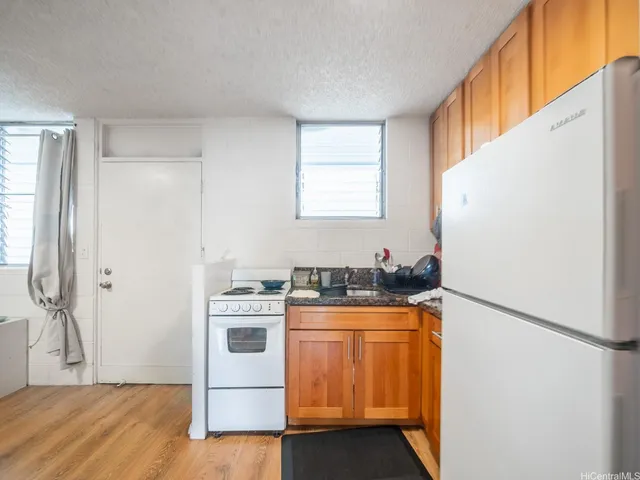 a kitchen with granite countertop a refrigerator a sink a stove and white cabinets