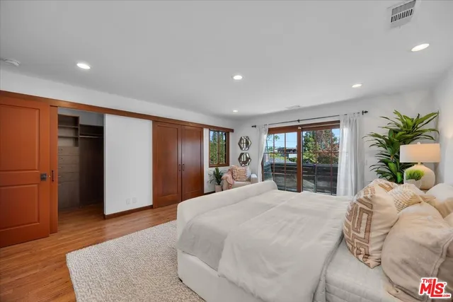 a large bedroom with a bed and wooden floor