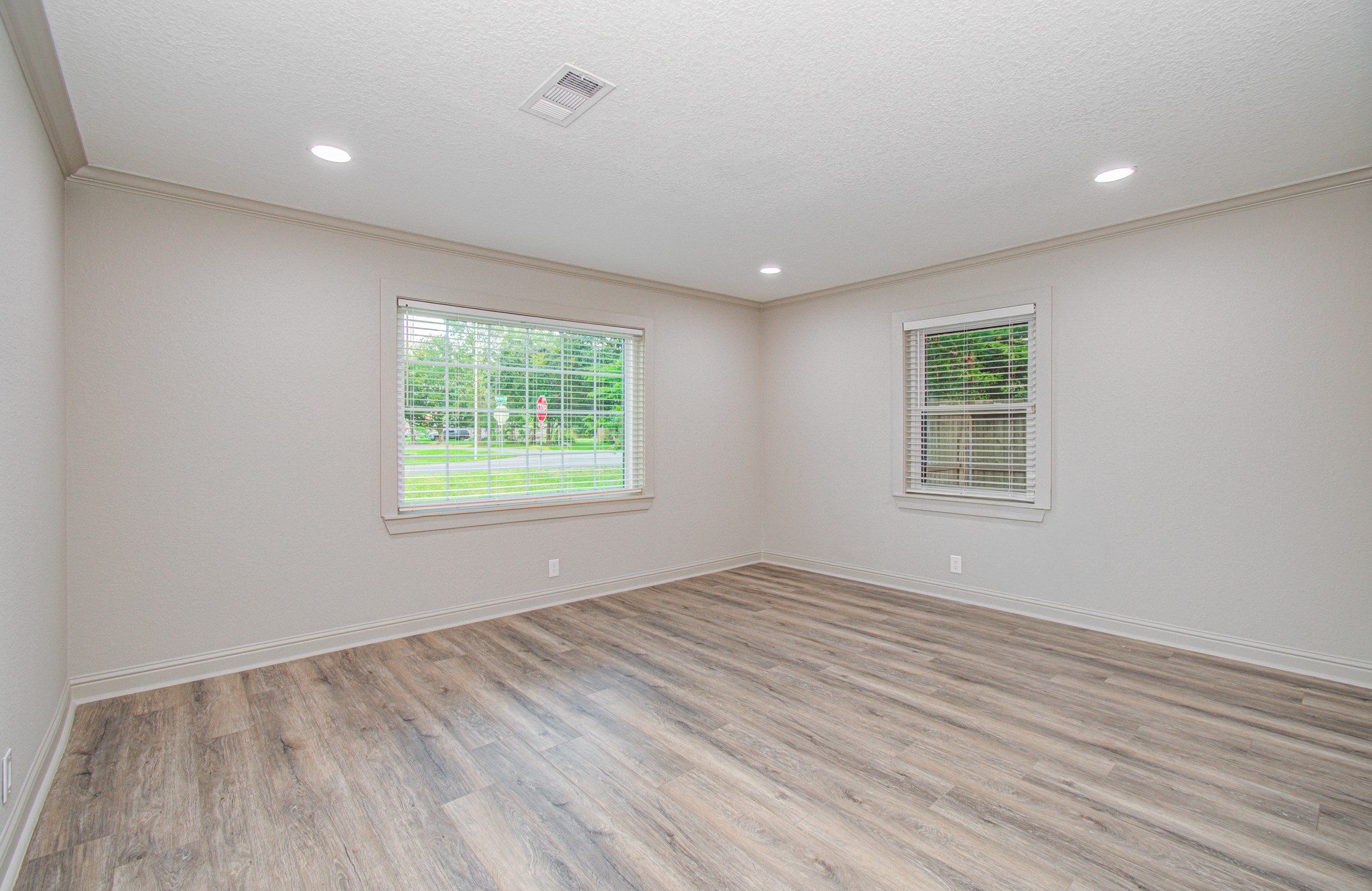 1801 Benbow Way Houston, TX 77080 - Photo 27 of 32 This bright, spacious room features light-colored walls and wood-look flooring, with large windows offering abundant natural light and views of the greenery outside. Perfect for a living or lounge area.