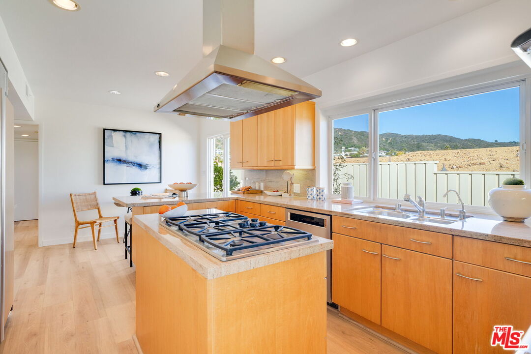 18332 Wakecrest Drive Malibu, CA 90265 - Photo 13 of 30 a kitchen with stainless steel appliances granite countertop a stove a sink dishwasher and white cabinets with wooden floor