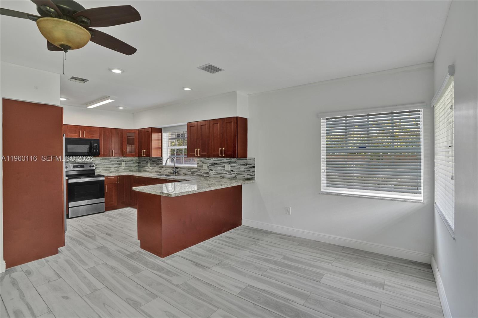 5721 Southwest 11th Street West Miami, FL 33144 - Photo 8 of 44 a large kitchen with stainless steel appliances granite countertop a stove and a wooden floors