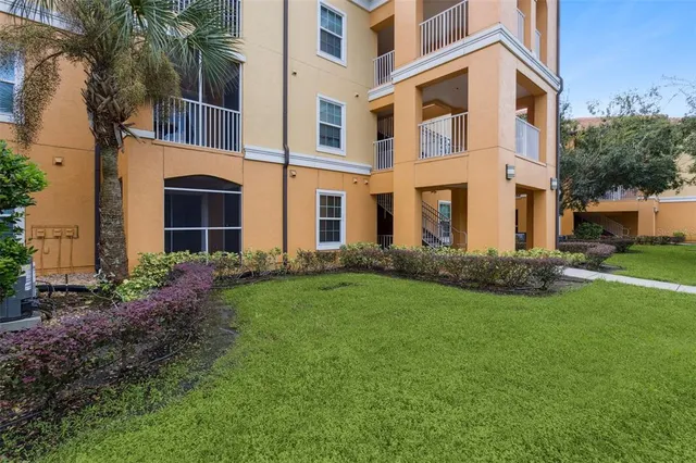 a view of a building next to a yard with plants and trees