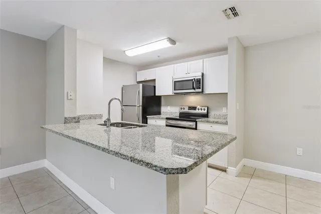 a kitchen with granite countertop a sink a stove and cabinets