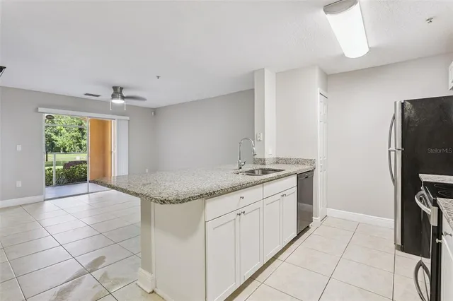 a kitchen with granite countertop a sink a counter top space appliances and cabinets
