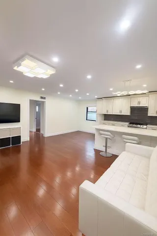 a living room with stainless steel appliances furniture and a kitchen view