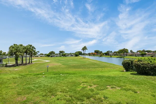 a large kitchen with stainless steel appliances kitchen island granite countertop a stove a sink dishwasher a refrigerator and white cabinets with wooden floor