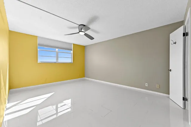 a view of an empty room with wooden floor and a ceiling fan