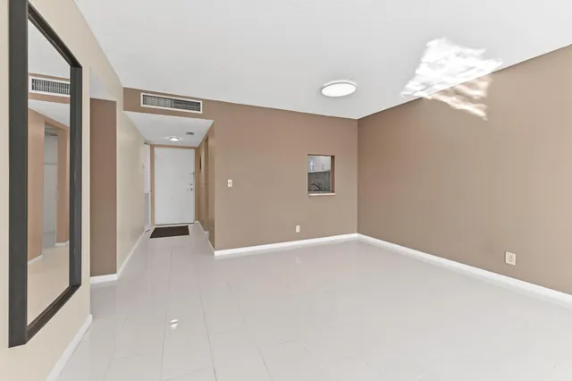 an empty room with chandelier fan and windows