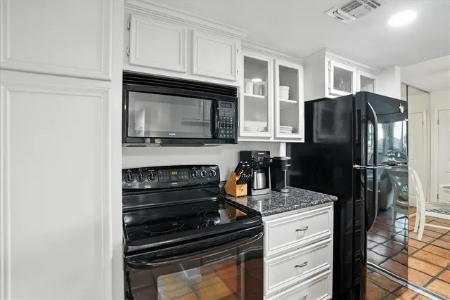 a kitchen with granite countertop a refrigerator stove and microwave