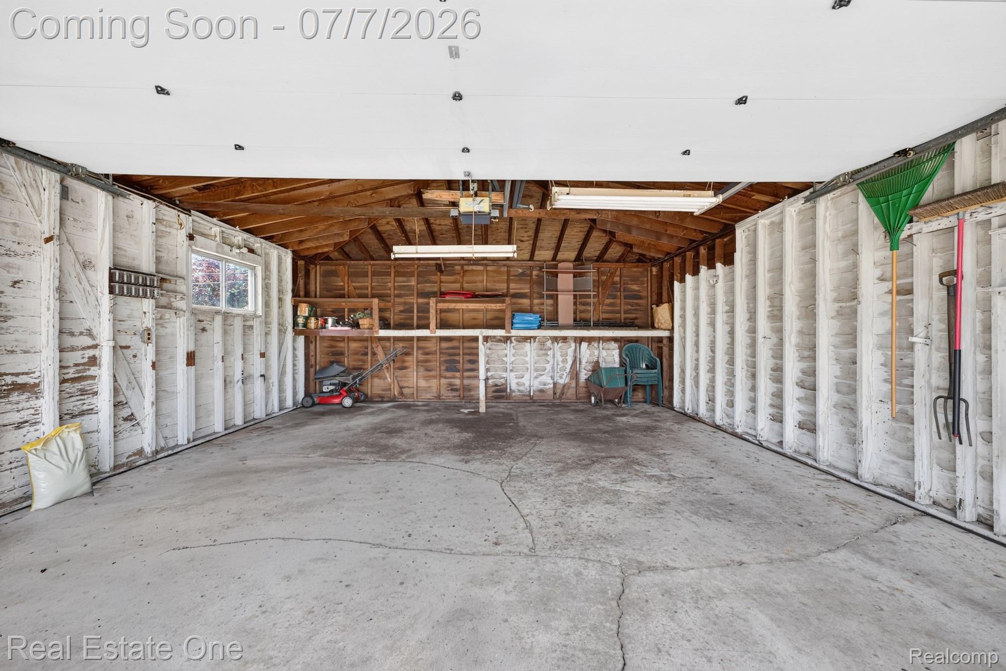 24749 Munson Street Taylor, MI 48180 - Photo 24 of 28 Spacious garage with concrete flooring, exposed wood beam ceiling, built-in shelving, a window, and fluorescent overhead lighting