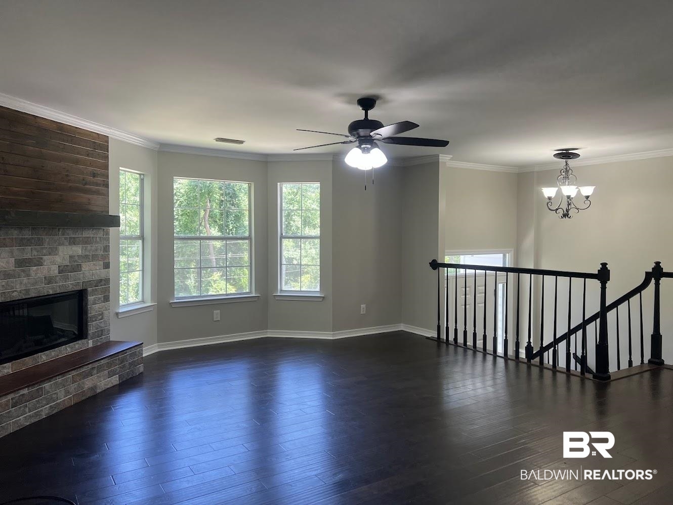 266 Ridgewood Drive Daphne, AL 36526 - Photo 6 of 34 Spacious living area featuring dark wood-finish flooring, a stone-faced fireplace with a wood mantle and hearth, and a bay window configuration
