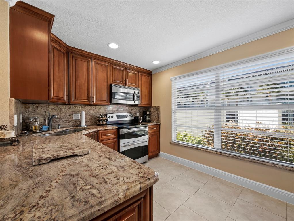 4430 Exeter Drive, Unit M108 Longboat Key, FL 34228 - Photo 5 of 65 a kitchen with granite countertop a stove a sink and a microwave