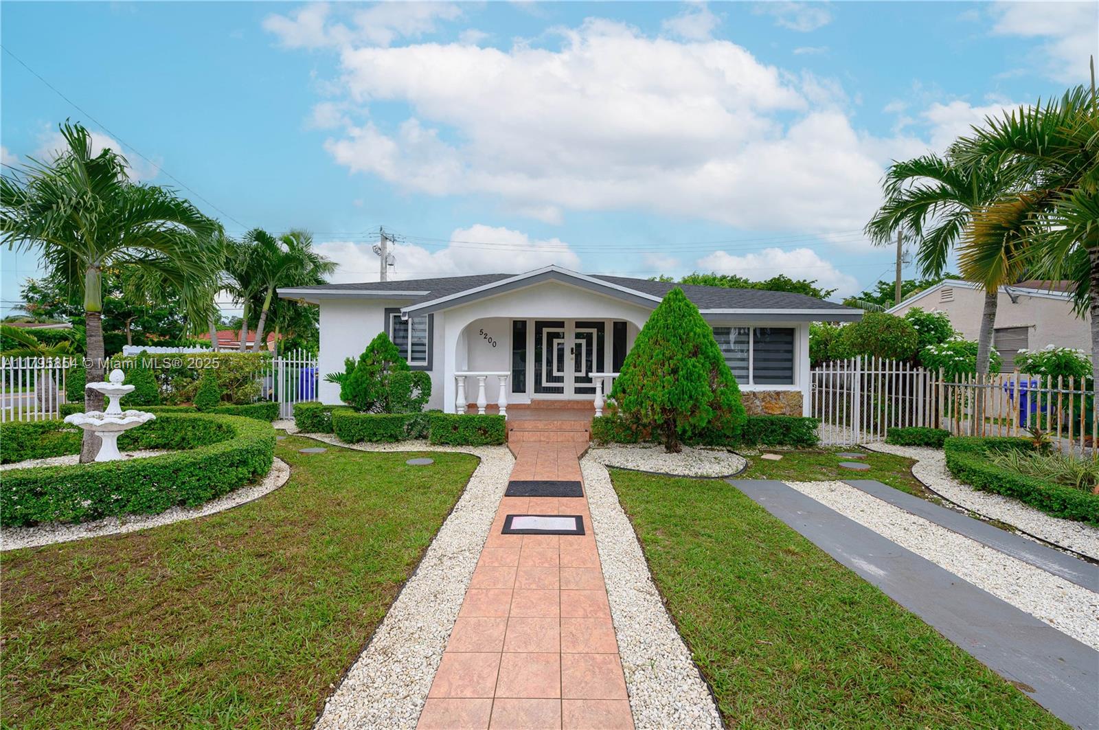 a front view of a house with a yard and potted plants