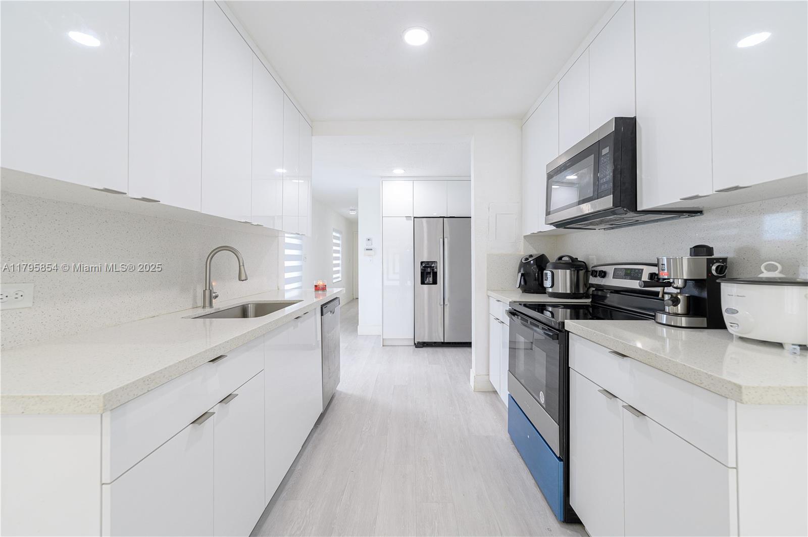 5200 Southwest 4th Street Miami, FL 33134 - Photo 16 of 35 a kitchen with white cabinets sink and stainless steel appliances