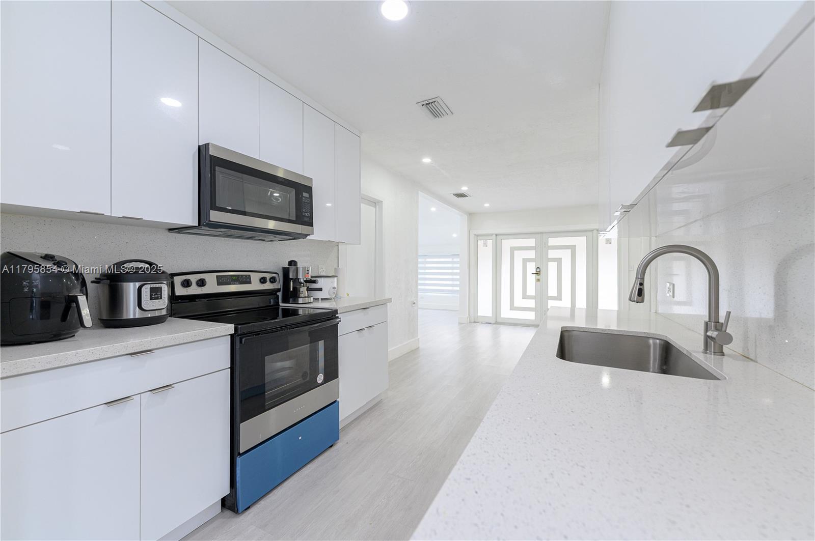 5200 Southwest 4th Street Miami, FL 33134 - Photo 19 of 35 a kitchen with stainless steel appliances granite countertop a sink dishwasher a stove and a microwave oven with white countertops