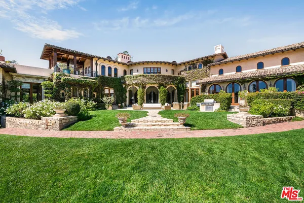 a view of a house with a big yard and large trees