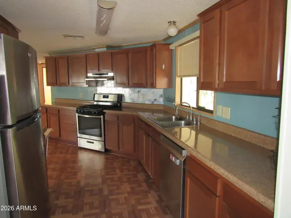 a kitchen with stainless steel appliances granite countertop a sink a stove a refrigerator cabinets and a window