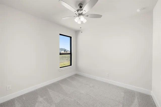 an empty room with a chandelier fan and windows